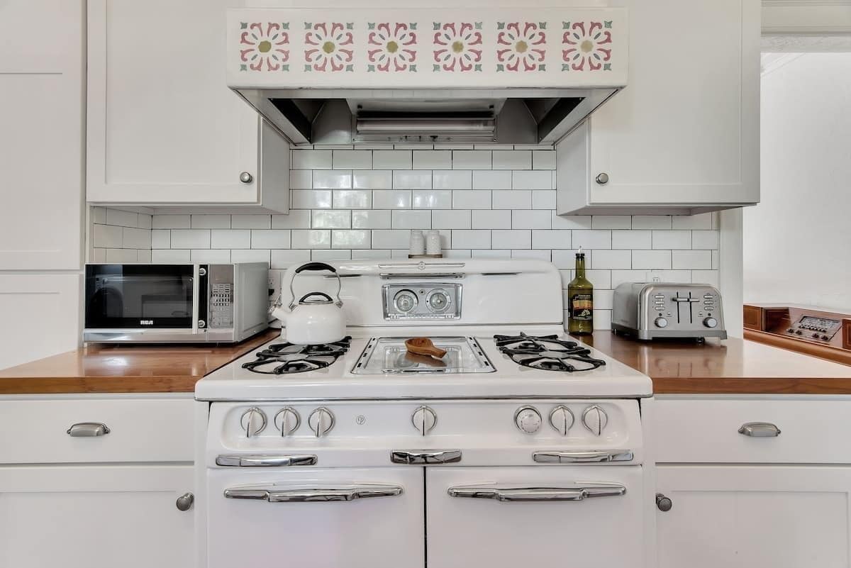 A kitchen with white cabinets, a microwave, a toaster, and a stove.