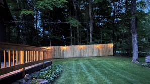 Un jardin bien entretenu avec une terrasse en bois, un muret en pierre et une clôture en bois.