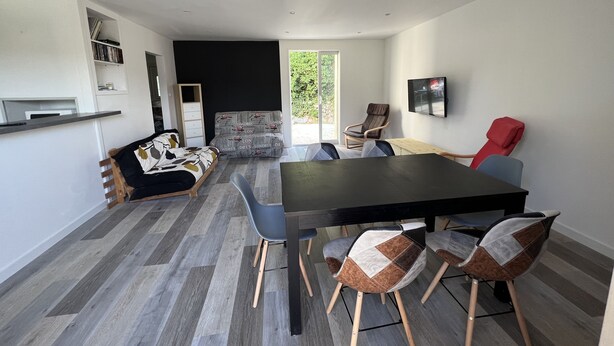 A modern interior with a dining area, a sofa, and a TV.