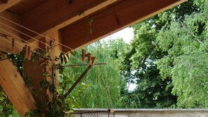 En träbänk under en pergola med utsikt över en trädgård och en stenmur.