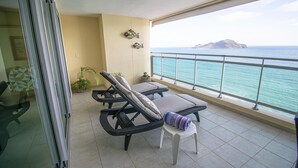 Ein Balkon mit zwei Liegestühlen, einem kleinen Tisch und einem Blumentopf.
