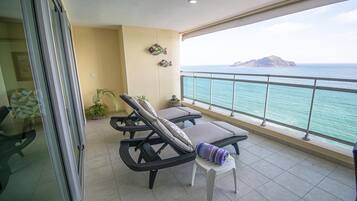 A balcony with two lounge chairs, a small table, and a potted plant.