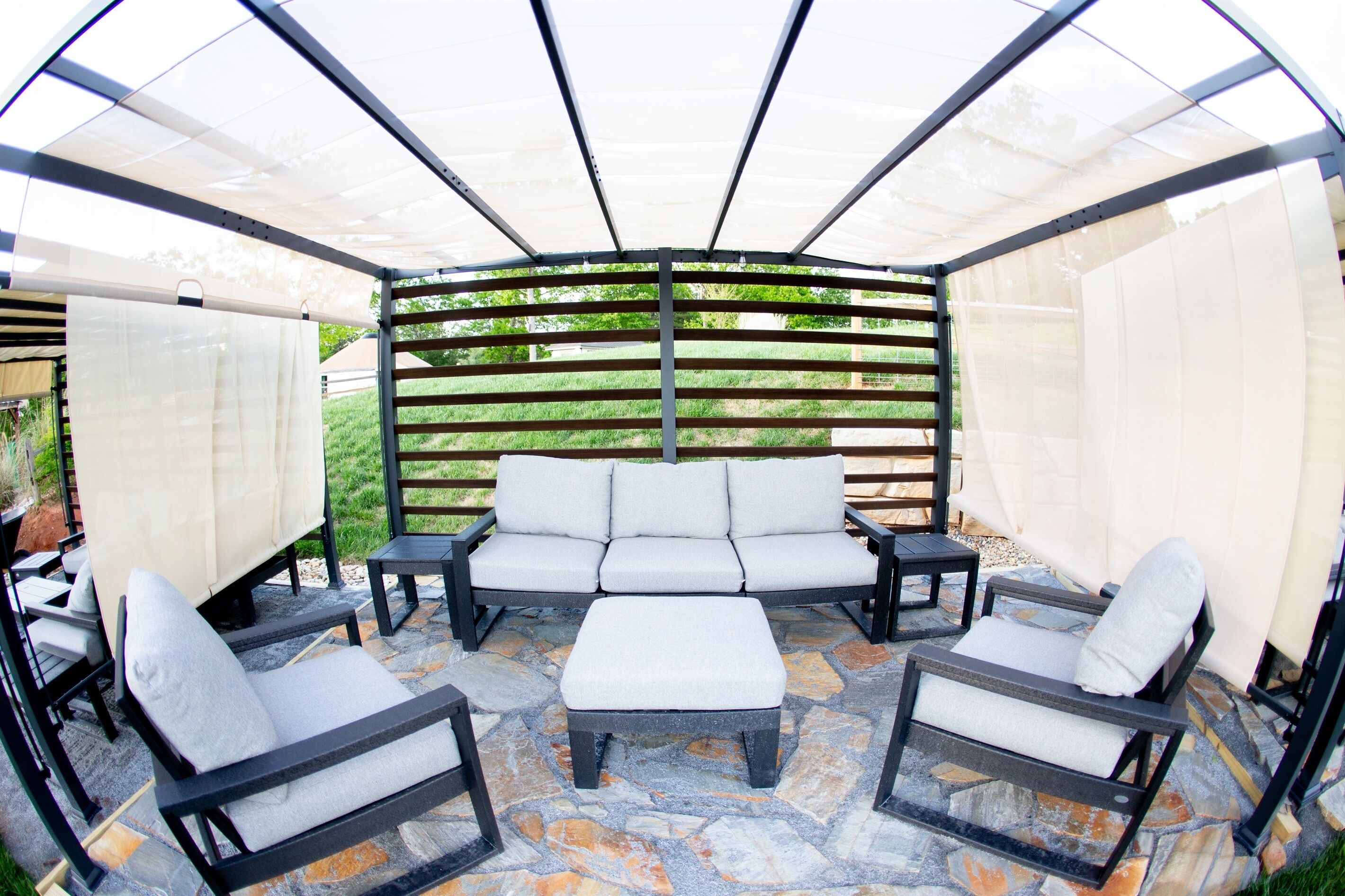 Eine überdachte Terrasse mit einer Eckcouch, zwei Sesseln und einem Couchtisch.
