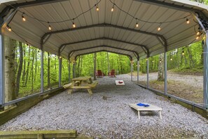 An outdoor covered area with a picnic table, chairs, and string lights. - Hidden Ridge - Secluded on 80 Acres (Nelsonville)
