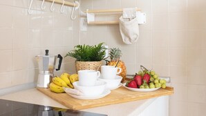Un comptoir de cuisine avec une machine à café, des bananes, un ananas et un saladier de fruits.