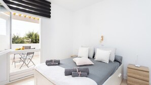 Une chambre à coucher moderne avec un lit, des oreillers, une table de chevet et une vue sur l’extérieur.