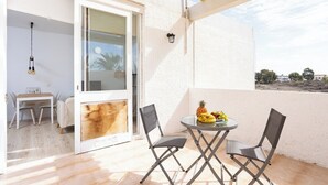 Une terrasse extérieure avec une table et des chaises, une porte vitrée donnant sur une pièce intérieure et une vue sur le paysage environnant.