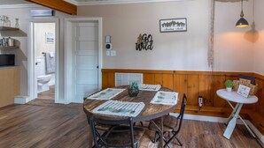 A dining area with a wooden table, chairs, and a bench. There is a kitchen area with a sink and cabinets visible in the background. - Hill Hideaway Unit 2 - Pet-Friendly Lake Retreat (Minocqua)