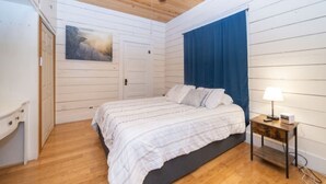 Une chambre à coucher avec un lit, une table de chevet, un ventilateur de plafond et une porte.