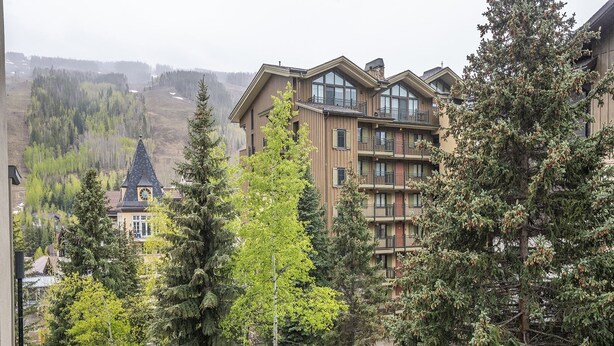 A multi-story building with balconies, surrounded by dense trees. - Westwind 407 (Vail)