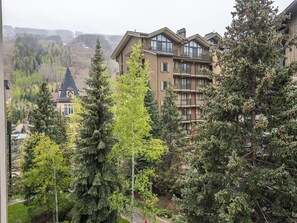 A multi-story building with balconies, surrounded by dense trees. - Westwind 407 (Vail)