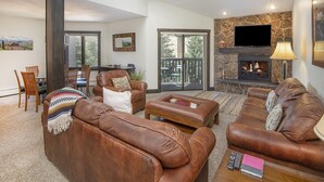 A spacious living room with leather sofas, a fireplace, and a television. - Westwind 407 (Vail)
