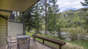 A wooden deck with a table and chairs, overlooking a mountainous landscape.