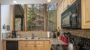 A kitchen with wooden cabinets, granite countertops, a stainless steel sink, a coffee maker, and a Samsung stove.