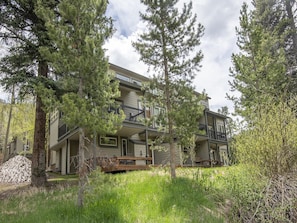 Stunning two-story residence with a balcony on each floor, set amidst a serene natural landscape with mature trees and a grassy area.