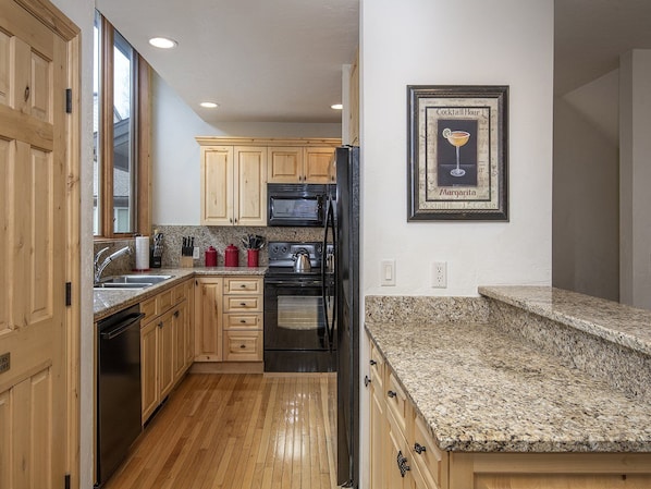 Enjoy cooking in this well-equipped kitchen with a granite countertop, light wood cabinetry, and stainless steel appliances.