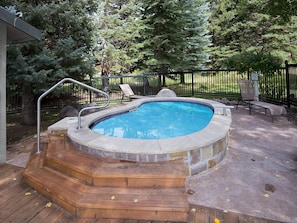 Relax by the pool surrounded by a deck and lush greenery.