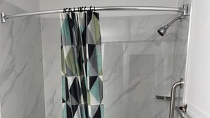A bathroom with a shower, toilet, and marble walls. - Executive Inn of Purcell (Purcell)
