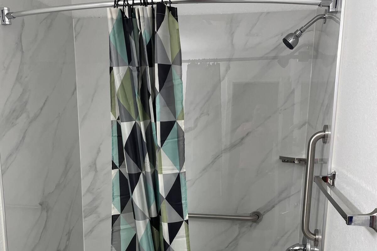 A bathroom with a shower, toilet, and marble walls.