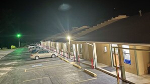 A parking lot with cars and a building with a ramp leading to the entrance. - Executive Inn of Purcell (Purcell)