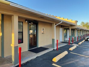 Une rangée de chambres de motel avec une seule entrée, chacune étant dotée d’une porte et d’une fenêtre.