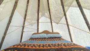 Un lit recouvert d’une couverture à motifs et agrémenté d’oreillers, le tout installé à l’intérieur d’une structure ressemblant à une tente.