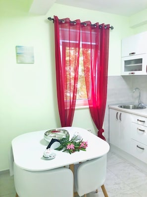 A small kitchen with white cabinets, a sink, and a table with chairs.