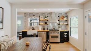 A modern kitchen with a wooden dining table, built-in appliances, and patterned backsplash. - NEWLY RENOVATED Pet Friendly Home (Big Bear Lake)