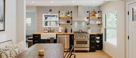 A modern kitchen with a wooden dining table, built-in appliances, and patterned backsplash.