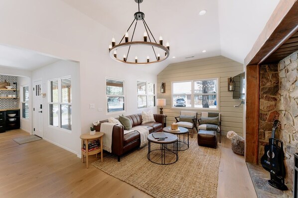 A spacious living room with a fireplace, a large chandelier, and a cozy seating area.