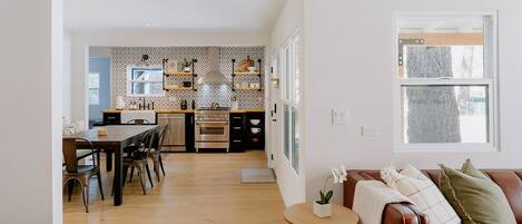 Eine moderne Küche mit Essbereich, Holzböden und einem gemütlichen Wohnbereich mit Ledersofa und kleinem Tisch.