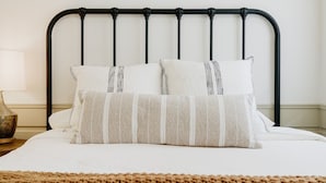 A bed with a black metal headboard, two pillows, a bedside lamp, and a woven rug. - NEWLY RENOVATED Pet Friendly Home (Big Bear Lake)