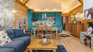 A cozy living room with a sofa, a wooden coffee table, and a dining area with a table and chairs. - Villa Raphael near Pirin Golf Resort (Razlog)