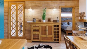 A wooden interior with a bed, a dining table, and a cabinet with drawers. - Villa Raphael near Pirin Golf Resort (Razlog)