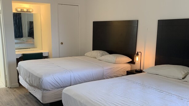 Une chambre d’hôtel avec deux lits, un miroir, une coiffeuse et une porte.