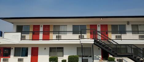 A two-story building with red doors numbered 201, 202, 203, and 204.