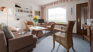 A cozy living room with a sofa, two wicker chairs, a coffee table, and a television. - Ferienhaus Mien Huske (Norderney)