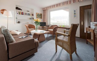 Ein gemütliches Wohnzimmer mit einer Couch, zwei Korbstühlen, einem Couchtisch und einem Fernseher.