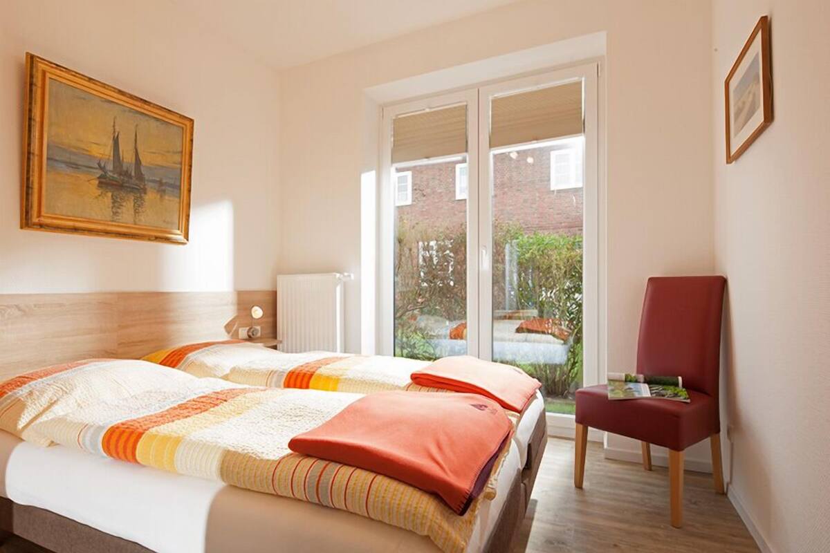Una habitación de hotel con dos camas, una silla roja y un ventanal con vistas a la vegetación.