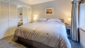 Ein Schlafzimmer mit Bett, Nachttischen, einem Kleiderschrank und einer Pendelleuchte.