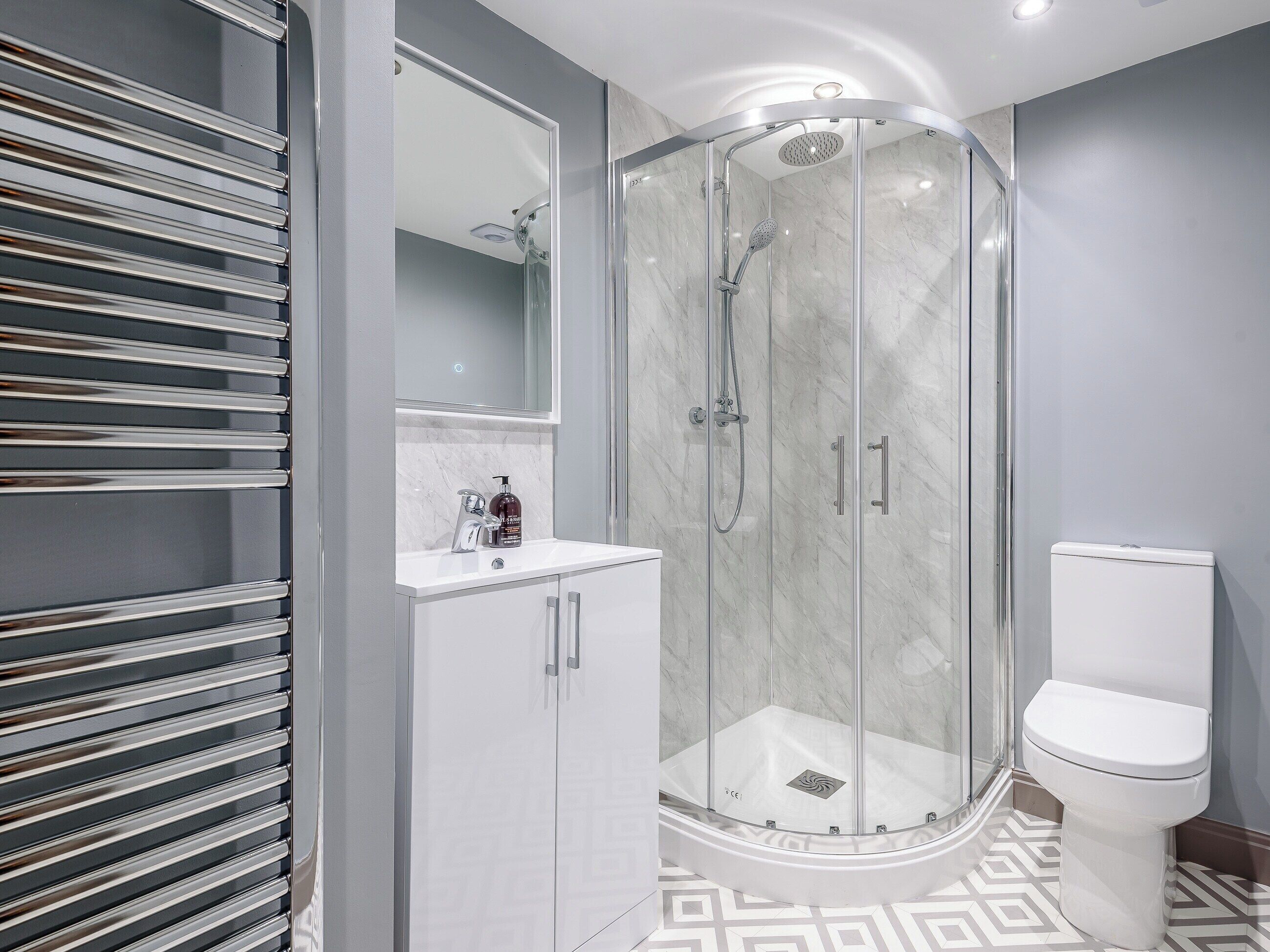 A modern bathroom with a glass-enclosed shower, a white toilet, and a vanity with a mirror.