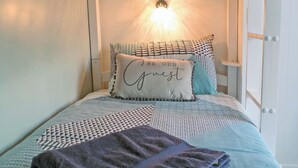 Een net opgemaakt bed met beddengoed met een patroon en een decoratief kussen met tekst.