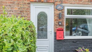 A white door with a glass panel, a red post box, and a window with a view of the outside.