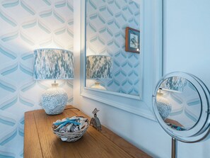 Un baño con tocador de madera, dos lámparas de pared, un cuenco decorativo y un espejo.