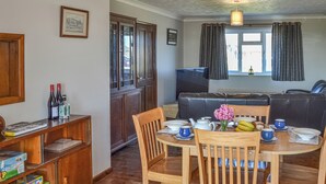 Een gezellige woonkamer met een houten eettafel, stoelen, een bank en een televisie.