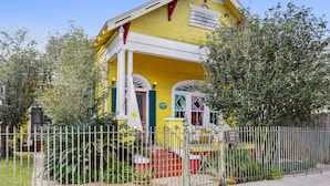 A yellow house with a porch, a white fence, and a staircase leading to the front door. - Auld Sweet Olive Bed & Breakfast (New Orleans)
