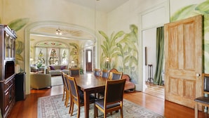 A dining area with a large wooden table, six chairs, and a patterned rug. - Auld Sweet Olive Bed & Breakfast (New Orleans)