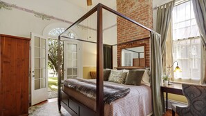 A four-poster bed with a brick wall and a window with curtains. - Auld Sweet Olive Bed & Breakfast (New Orleans)