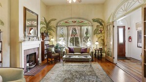 A spacious living room with a fireplace, a sofa, and a coffee table. - Auld Sweet Olive Bed & Breakfast (New Orleans)