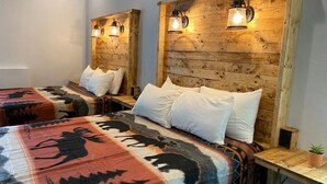 Habitación con dos camas, cada una con cabecero de madera y lámparas fijadas a la pared.